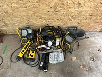 Overview photo of all items including power strips, cords, portable floodlights, flashlight, electrical tape, and radio