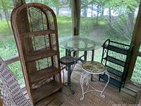 Wide view showing all items included in the lot: large rattan shelf, smaller black rattan shelf, glass-top table, mosaic-top stool, and small black metal stool.