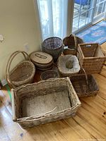 All baskets grouped on wooden floor showing varied sizes, shapes, and handles.