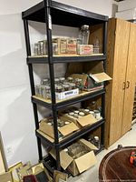 Full view of black plastic shelving unit loaded with jars and boxes (contents not included) positioned in a room next to a wooden cabinet