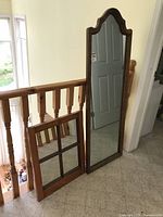 Both mirrors pictured upright leaning against stair railing, showing full size and shape difference