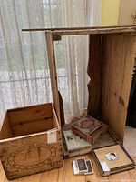 Various vintage collectible wooden boxes and framed items displayed inside a large wooden frame, showing minor wear and structural damage