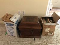 Closed wooden gramophone cabinet flanked by two boxes of records