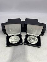 Two silver-toned NYSE Euronext medallions in open black cases with white lining and NYSE Euronext branding visible.