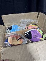 Open cardboard box containing multiple colorful ceramic fish-shaped trinket boxes wrapped in bubble wrap.