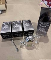 Four Wm. A. Rogers silver-plated snail-shaped saltcellars in original Tarnish Resistant Silver Saltcellar Snail boxes. One snail and small spoon shown outside box on table.