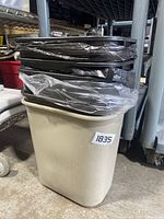 Beige plastic desk trash cans stacked with black lids and black trash bags inside, showing the full set and individual details.
