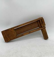 Side view of antique wooden noisemaker clacker showing rectangular body, handle, and internal clappers