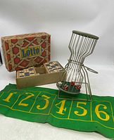 Full view of the lot showing the Lotto game box, cloth game board, and the Chuck A Luck dice tumbler with dice inside.