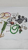 Full lot of costume jewelry on white background, showing bracelets, necklaces, rings, earrings, pendants, and keychain grouped together.