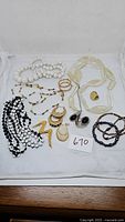 Grouping of various costume jewelry pieces laid out with a lot number tag '670'.