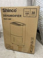 Front view of the Shinco dehumidifier box showing product name, model SDZ1-30P, capacity of 30 pints per day and suitable room size of 1500 sq ft.