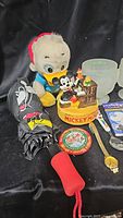 Overview of Disney collectibles including Donald Duck plush, Mickey Mouse music box, umbrella, badge, wristwatch, and glass cups on black background.