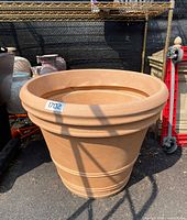 Extra large tan plastic flower pot showing rounded top rim and decorative horizontal ridges on the body