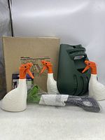 Overall photo showing three duck-shaped spray bottles, two green hand scoops, a black shovel handle, and the original box for the scoops