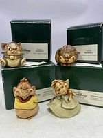 Front view of all four Harmony Kingdom Disney figures with their original green boxes visible behind them.