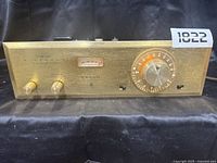 Front view of the unit showing tuning dial, level and selector knobs, tuning meter, and branding.