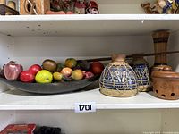 Wide view showing black platter with assorted artificial fruit and three ceramic items including two Moroccan bongo drums, a vase, and brown jar