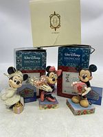 Three Disney figurines from Jim Shore Walt Disney Showcase Collection and Lenox 2003 Minnie Mouse Christmas ornament shown with original boxes and tags.
