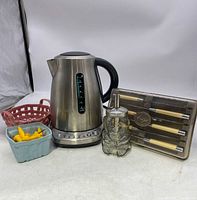 Front view of the electric kettle, cutlery set, glass honey pot, and ceramic containers together