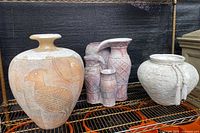 Group view of five ceramic outdoor garden pieces including large bird etched vase, additional etched vases, and round pot with rope detail
