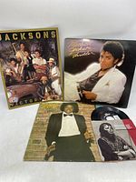 Photo of all items showing Michael Jackson 'Thriller' LP, Michael Jackson LP album, Jacksons Victory tour guide, and a 45 RPM single record.