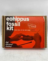 Front view of the Eohippus fossil kit box showing the title and shadows of hands holding fossil replica.