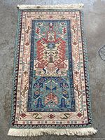 Full view of the Navajo style rectangular area rug with central intricate patterns and frontal fringe.