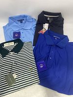 Four new golf shirts laid out, colors visible: light blue, dark navy, royal blue, green & white stripes
