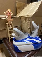 Photo showing a ceramic shark trinket dish with lifeguard figurine sitting on lifeguard chair behind it