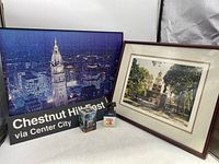 Framed city night skyline puzzle, destination sign, and two souvenirs in front of framed Independence Hall photo