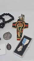 Overview of all items including the enameled cross pendant on chain, round St. Francis medal, oval medal, sterling medal pendant in box, and black bead rosary.