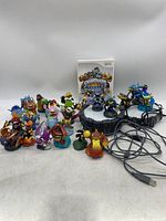 Wide view showing Skylanders game case, two portals with cables, and all 15 player figures arranged in front.