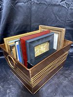 Metal container filled with framed art pieces showing side and top views