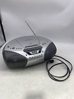 Front view of the silver Sony CFD-S250 CD radio cassette-corder with antenna raised and power cord visible, showing control buttons and display.