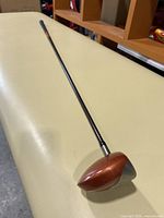 Full length view of the golf driver showing the shaft and club head with bronze metallic color.