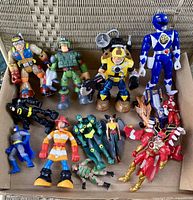 Top view of 13 assorted vintage action figures in a box, showing colors, accessories and types of figures.