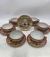Set of six porcelain teacups and matching saucers arranged in a semi-circle, showing the style and design of the set
