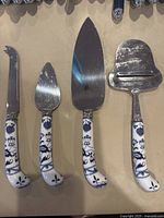 Top view of the four vintage kitchen tools showing the metal blades and blue floral patterned porcelain handles, arranged side by side