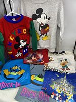 Full lot showing various Disney-themed T-shirts, sweatshirts, and sweater featuring Mickey Mouse and Donald Duck.