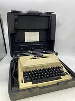 Vintage Sears The Scholar electric typewriter installed inside its black carry case, showing the full unit including the keyboard and top carriage.
