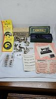 Wide view of vintage sewing machine parts including belts, metal attachments, bobbins, and Admiral branded parts with instructions laid out on a table