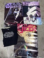 Three vintage Star Wars posters displayed, featuring Darth Vader, Stormtroopers, and Yoda, along with a black XL Star Wars T-shirt with white logo.
