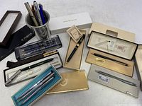 Overview of the pen group including boxed pens from Cross, Parker, and Barlow/Salm, as well as assortment of loose pens in a silver cup.