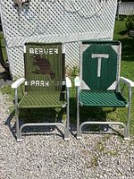 Front view of two woven lawn chairs placed outside on gravel and grass, showing beaver logo and 'T' design