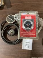 View showing three gauges including new amp gauge in package, pressure gauge with hose, and vacuum gauge.