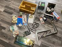 Overview of assorted hardware items including toolbox, hooks, brackets, light bulbs and packaging.