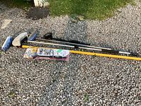 Lot showing all brushes, extension poles, and boxed Hyde Pivot nozzle wand arranged on gravel ground.