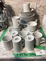 Full view of the stacked plates, bowls, and cups showing quantity and style.