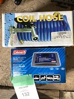Original packaging including coil hose and Coleman solar charge controller box with branding and specifications.